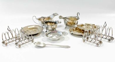 A collection of silverware including a cased set of four toast racks, sauceboats, ashtrays, cream