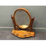 A Victorian mahogany swing mirror, the oval plate above a shaped base 83 x 72 x 28cm