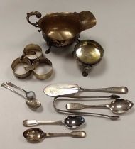 A collection of silverware including napkin rings, sauce boat, flatware, cauldron salt and a