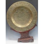 A Chinese circular brass dish on carved wood stand, early 20th century, decorated in relief with