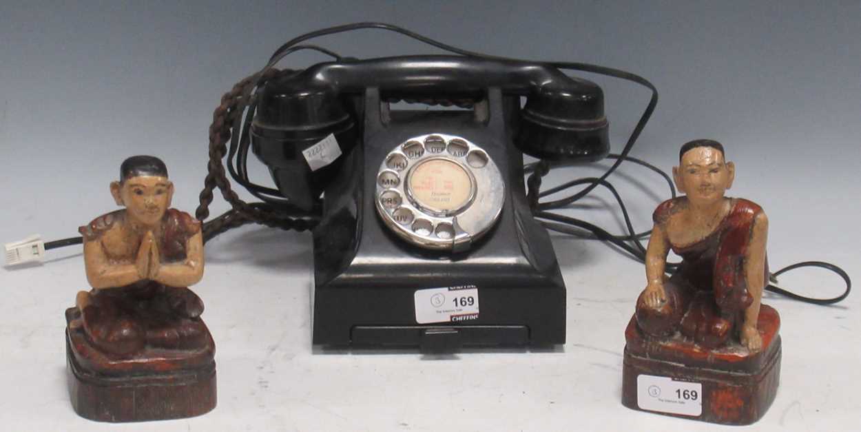 A bakelite desktop telephone with rotary dial and drawer to base, together with two carved wood