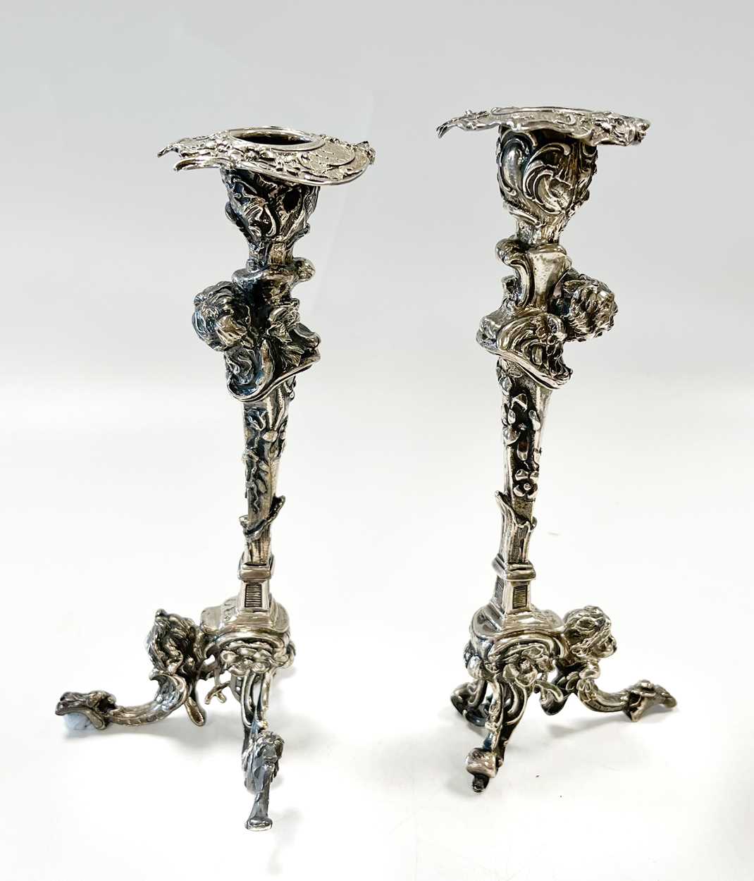 A pair of Continental silver cast candlesticks, decorated with heads, leaves and scrolls, damage and