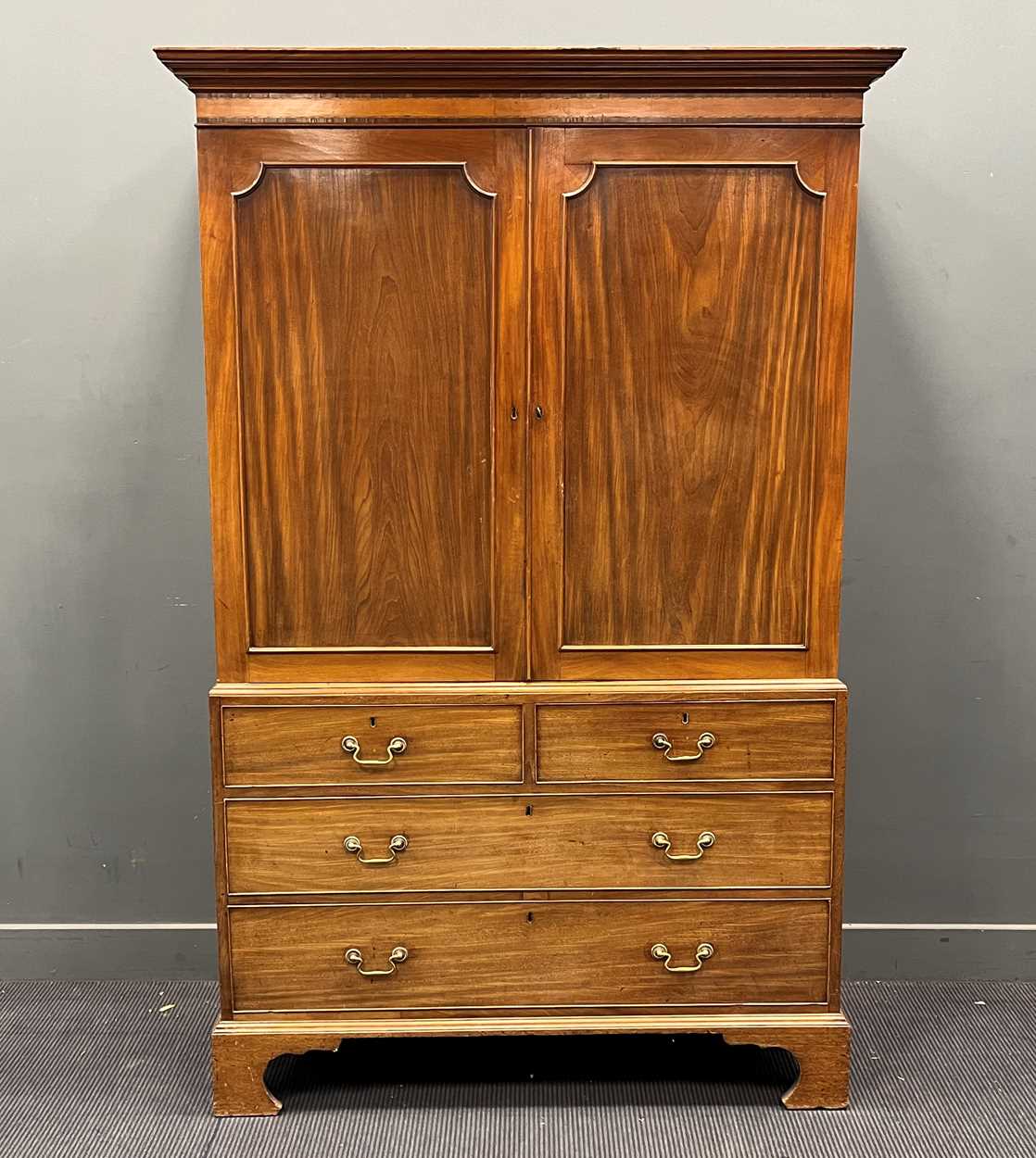 A late Georgian mahogany linen press with satinwood banded cornice over two panelled doors and 4