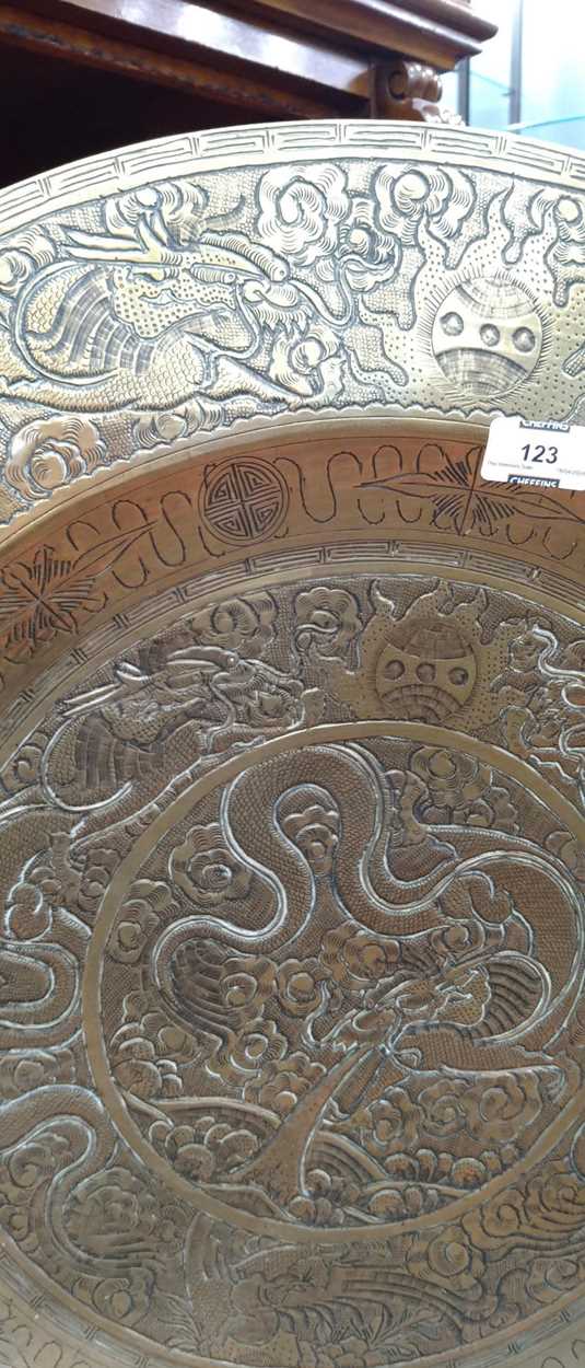 A Chinese circular brass dish on carved wood stand, early 20th century, decorated in relief with - Image 4 of 10