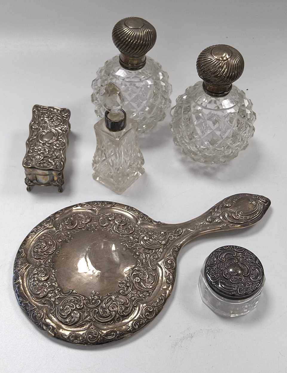 A silver hand mirror, a pair of silver topped glass scent bottles, another smaller, a silver