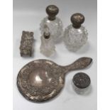 A silver hand mirror, a pair of silver topped glass scent bottles, another smaller, a silver