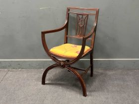 An Edwardian mahogany elbow chair of reeded x frame structure, supported by H-stretcher.