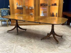 A Regency style dining table with double pedestal, each set on four reeded legs and brass casters.