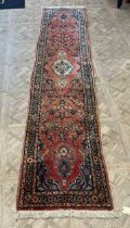 A red ground wool runner with deep pile, blue pattern design 415 x 78cm