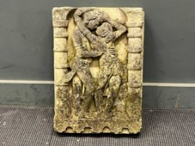 A weathered cast stone wall plaque, depicting two figures flanked by pillars after a 10th century