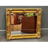 A rectangular gilt framed wall mirror, the bevelled plate within a moulded frame with acanthas