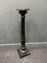 An ebonised pedestal, 20th century, the circular top over a turned and acanthus carved column on a