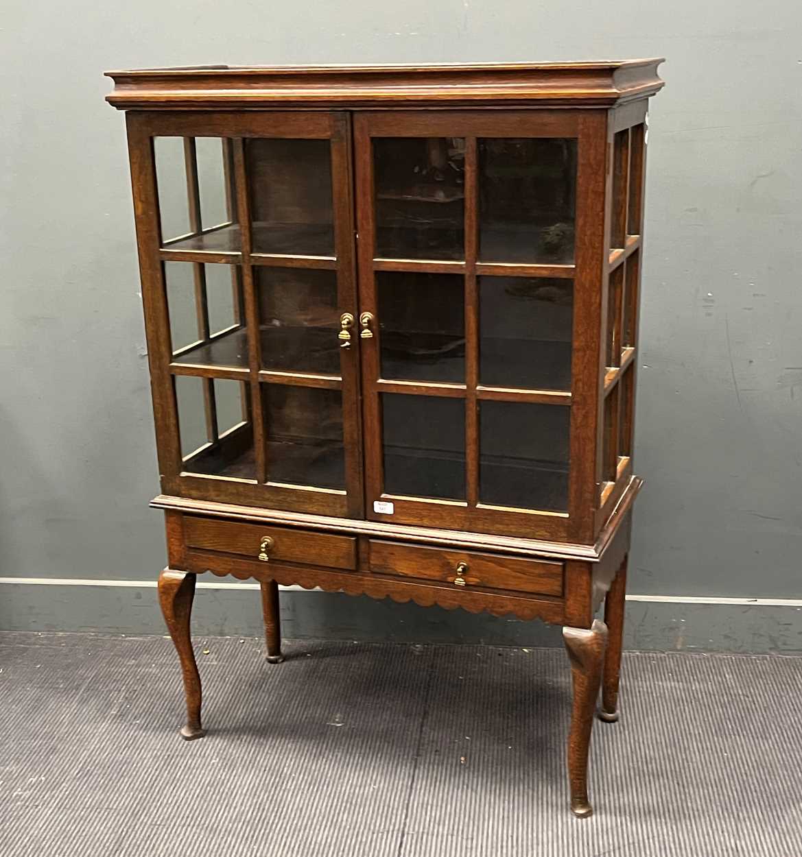 An Edwardian oak glazed cabinet on associated stand, two drawer base with scalloped frieze on