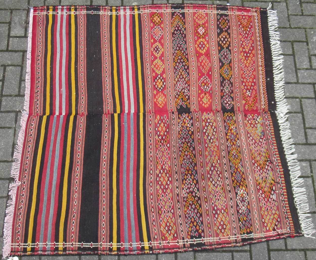 A flat weave tribal rug formed of two joined pieces, mainly in reds and yellows 148 x 158cm