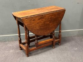 An 18th century oak drop leaf table, the oval drop flap top raised on ring turned supports 72 x 91 x