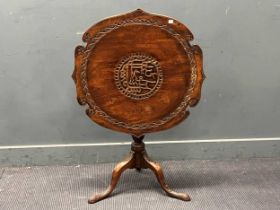 A mahogany snap top tripod table, with carved patterned shaped top on a baluster column and carved