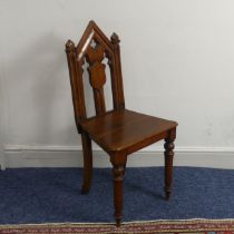 A Victorian oak gothic style hall Chair, with pierced back raised on turned front legs and splayed