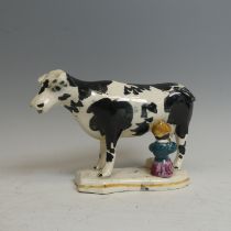 An antique Staffordshire Cow Creamer, modelled as being milked, lacks cover, damaged, H 13cm,