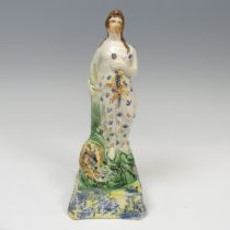 An early 19thC pearlware figure of Spring, decorated in prattware palette, modelled in typical
