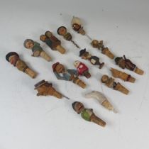 A collection of fourteen early 20th century carved wooden wine bottle stoppers, mostly