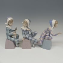 A Lladro Harlequin ABC Trio, each modelled in varying positions perched on letter blocks, tallest