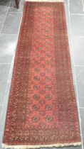 Tribal Rugs; a red ground Afghan runner, wool pile on wool base, 272cm x 82cm, pile worn in places.