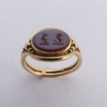 An 18ct yellow gold Signet Ring, the front set with an oval carnelian, carved with two mythical