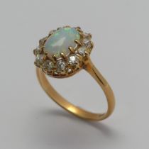 An opal and diamond cluster Ring, the central oval cabochon opal, approx. 8.8mm long, claw set