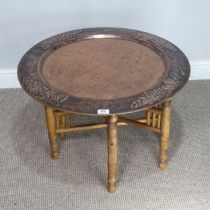 A large Arts and Crafts copper tray Table, outer rim embossed with stylised flowers, with folding