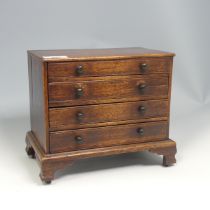 An antique oak miniature tabletop Chest of drawers, rectangular top over four long graduating