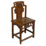 A 20th century carved Chinese hall Chair, scrollwork back with centre panel carved with figure and