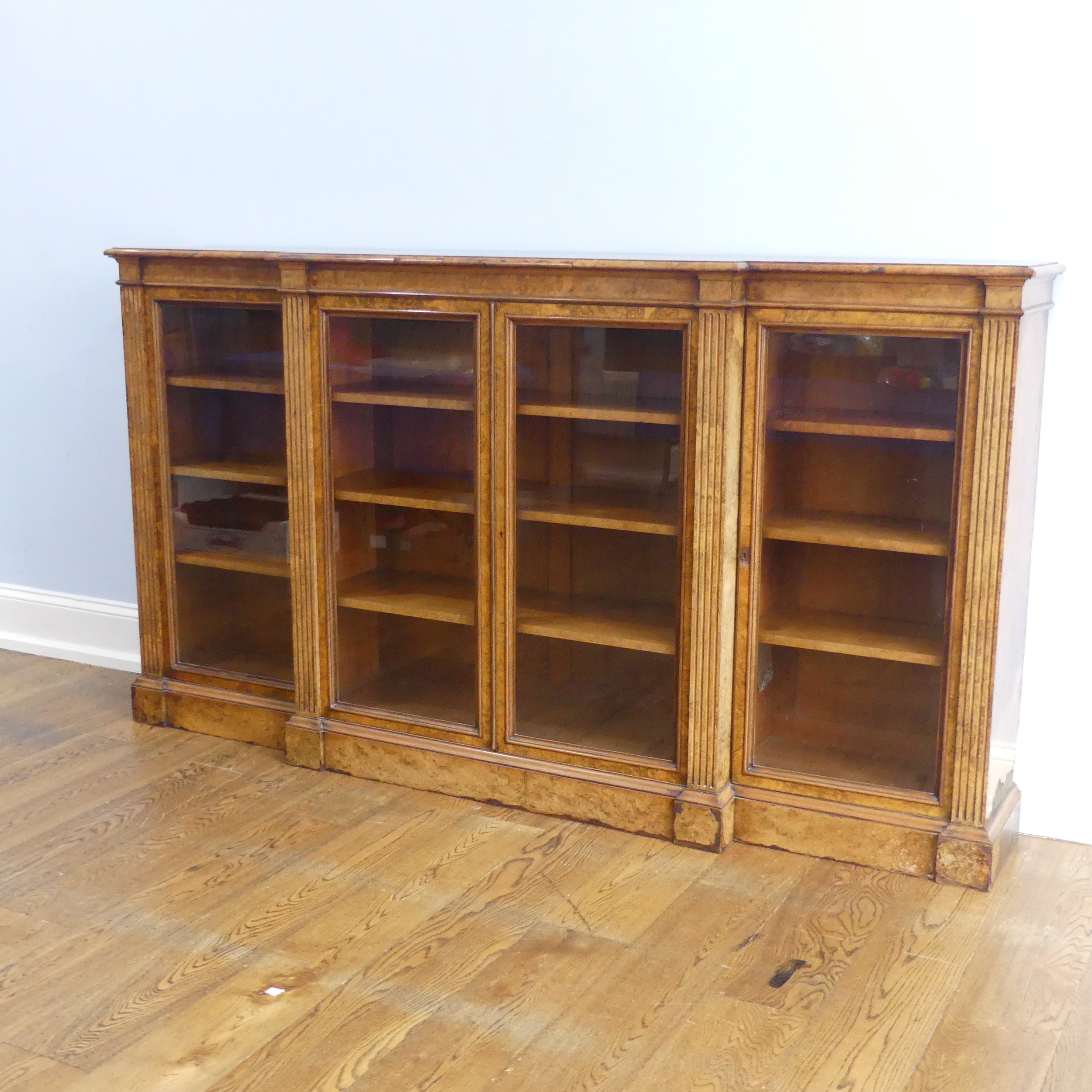A good Victorian burr walnut breakfront glazed Bookcase, shaped top over glazed doors and plinth