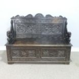 A late Victorian carved oak Settle, foliate carved backrest flanked by scroll arms in the form of