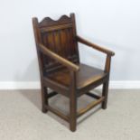 An 18th century wainscot style oak Armchair, shaped headrest over panelled backrest and flanked by