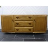 An Ercol "Windsor" blond elm Sideboard, model No. 455, fitted with three central drawers with an