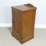 An Arts and crafts oak bedside Cabinet, pierced top over panelled doors, raised on shaped plinth