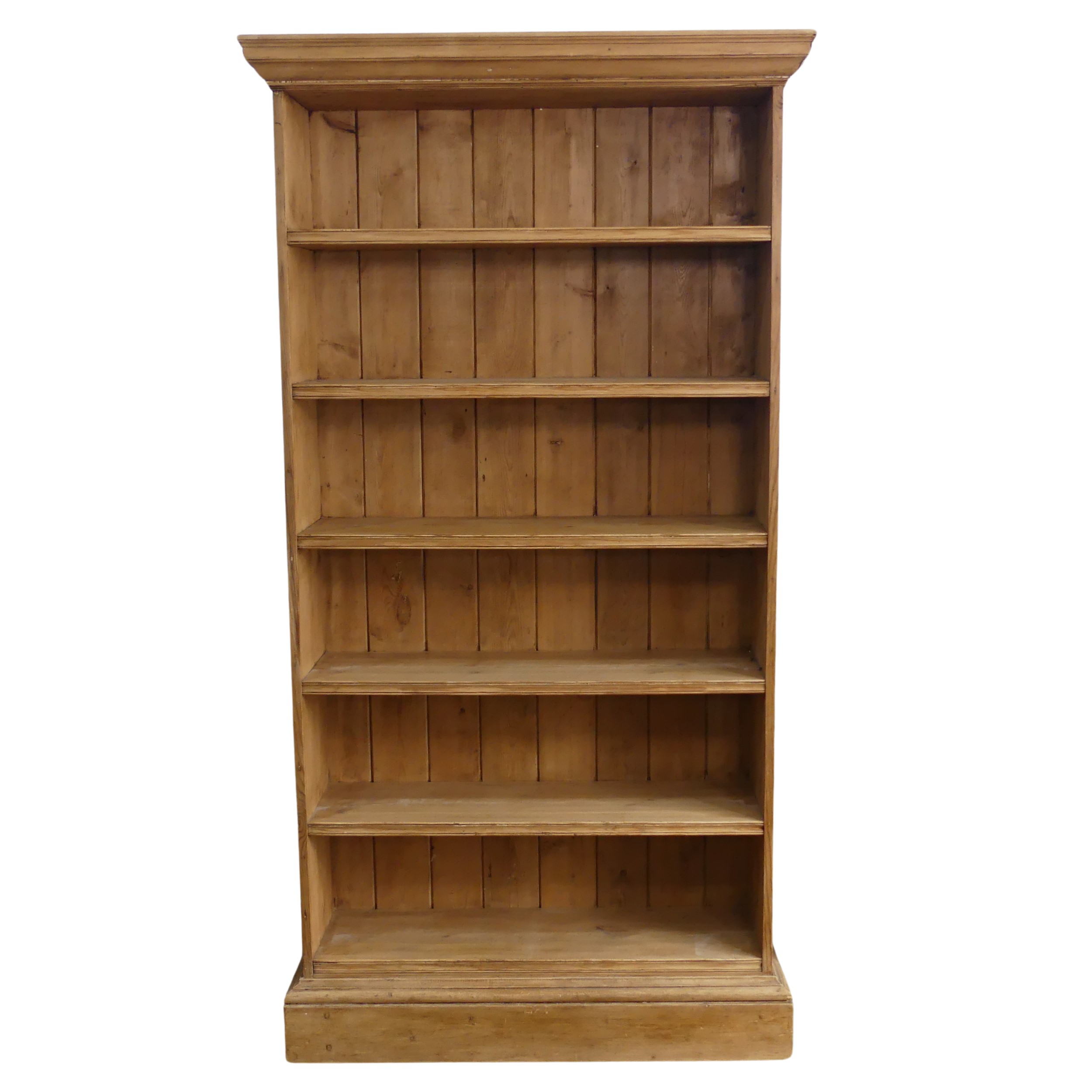 A large antique pine open Bookcase, moulded cornice over five deep shelves, raised on plinth base, W