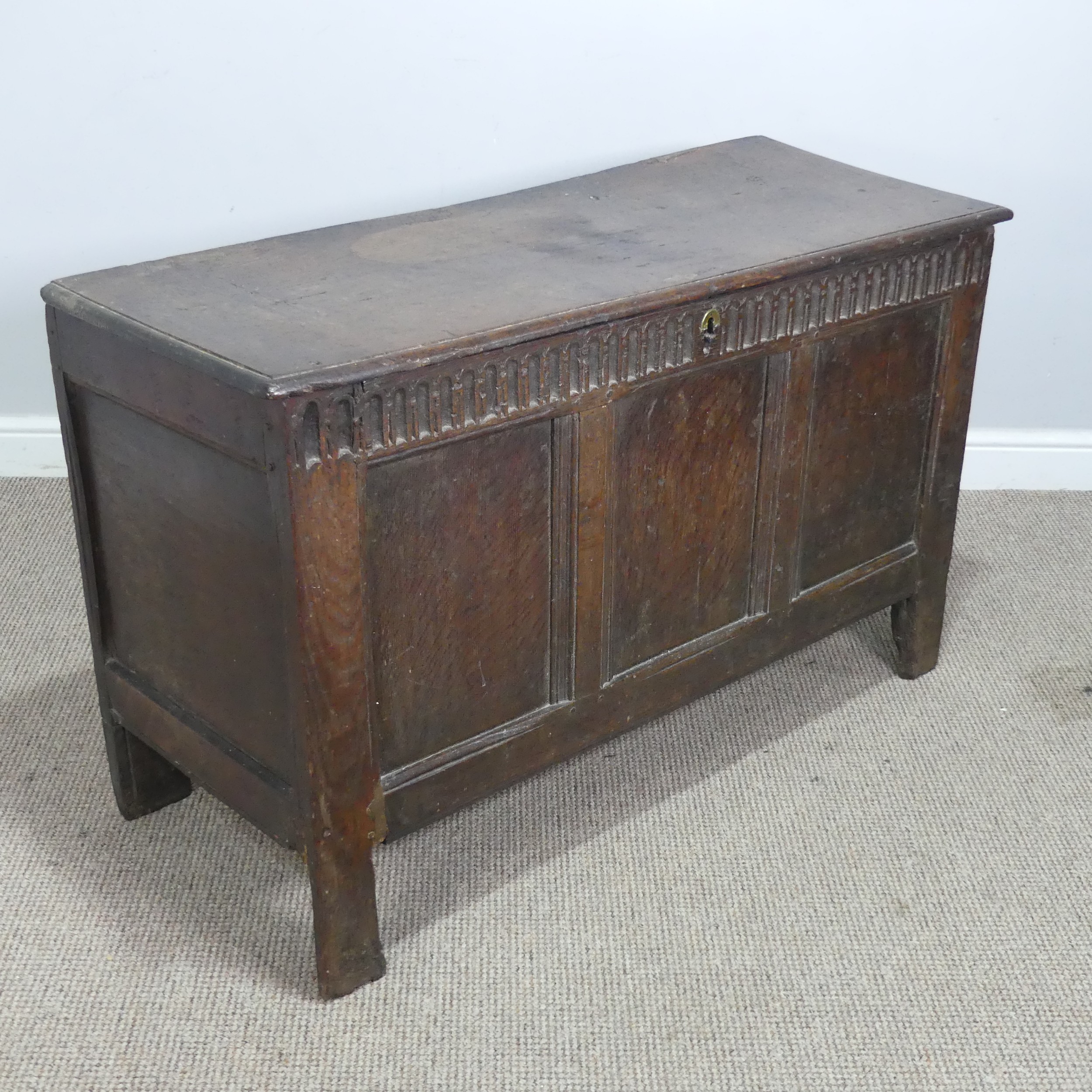 A 17th century and later oak three panel Coffer, rectangular top over carved frieze and three