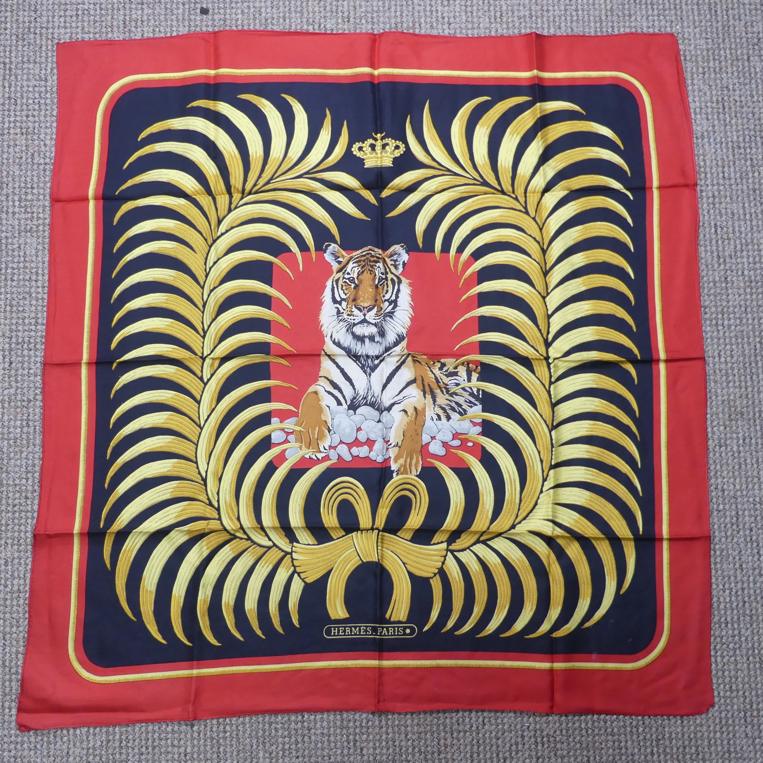 A Hermès silk twill scarf: Royal Tiger design, gold and black on red ground, hand rolled edges,