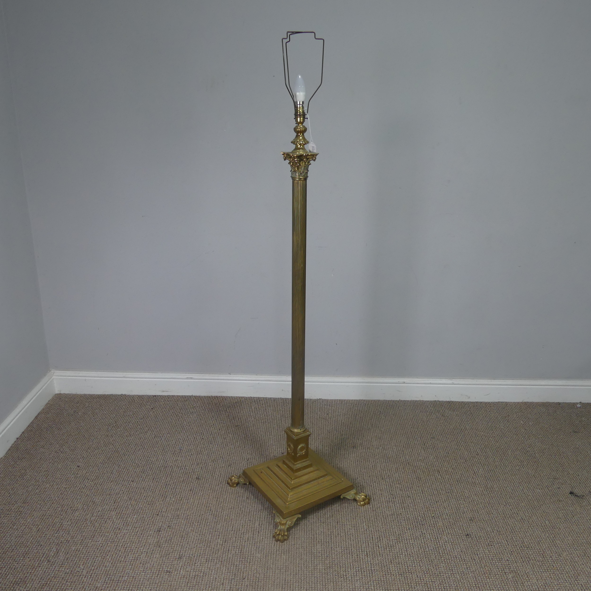 An antique brass standard Lamp, electrified, with corinthian column raised on stepped base and