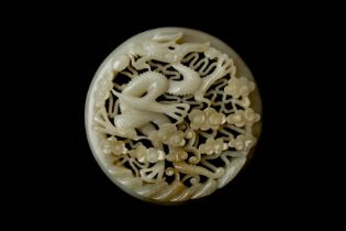 A CHINESE RETICULATED WHITE AND RUSSET JADE 'DRAGON' ROUND PLAQUE 十九世紀 白玉糖色龍趕珠紋珮