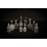 A group of ten cut glass decanters and some stoppers