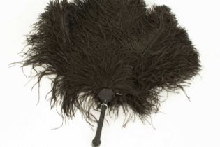 A black ostrich feather fan on a black carved handle