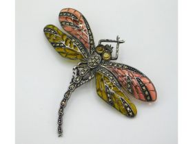 A detailed, silver dragonfly brooch set with marca