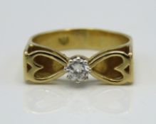 A yellow metal ring with heart shaped decor set wi