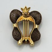 A yellow metal brooch of lyre shape with woven hai