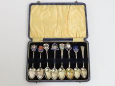A cased set of eight silver tourist type spoons with enamelled tops dating from 1908 onward, Barnard