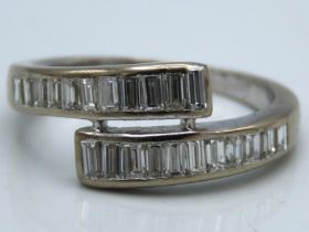 A white metal ring set with 22 baguette cut diamonds, tests electronically as 18ct gold, 4.2g, size