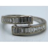 A white metal ring set with 22 baguette cut diamonds, tests electronically as 18ct gold, 4.2g, size