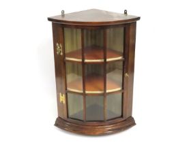 An antique glazed mahogany corner cabinet with bra